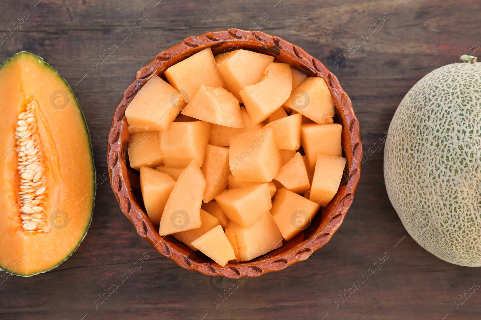 Photo of Whole and cut delicious ripe melons on wooden table, flat lay