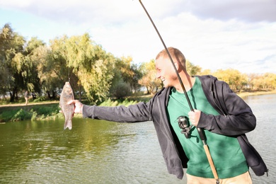 Photo of Man with rod fishing at riverside on sunny day. Recreational activity