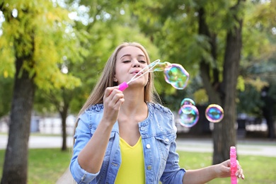 Young woman blowing soap bubbles in park
