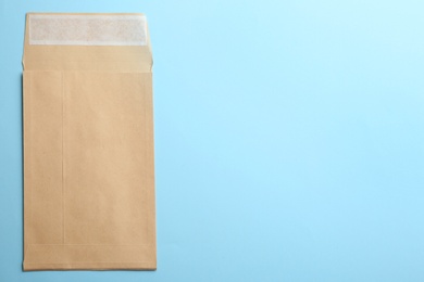 Photo of Kraft paper envelope on light blue background, top view. Space for text