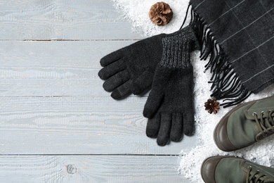 Photo of Stylish woolen gloves, scarf, pair of shoes and winter decor on grey wooden table, flat lay. Space for text