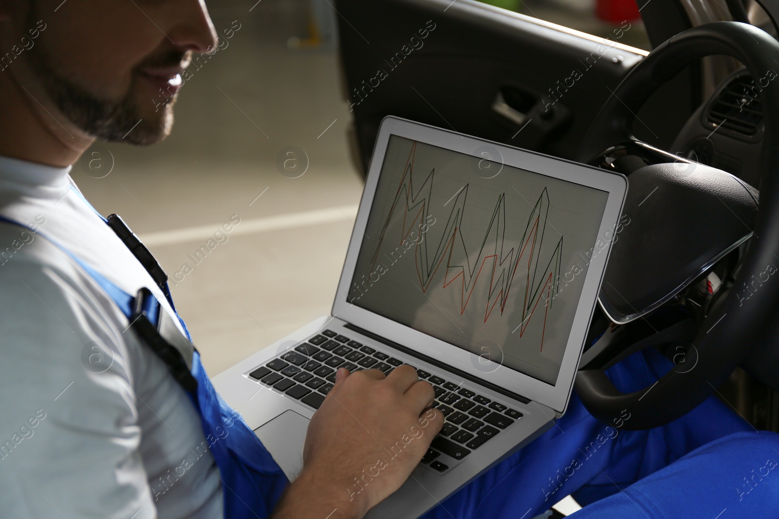 Photo of Mechanic with laptop doing car diagnostic at automobile repair shop, closeup