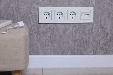 Electric power sockets on grey wall indoors, space for text