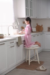 Little girl washing dishes in kitchen at home
