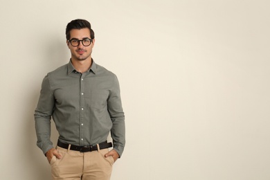 Young male teacher with glasses on beige background. Space for text