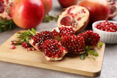 Delicious ripe pomegranates on grey table, closeup