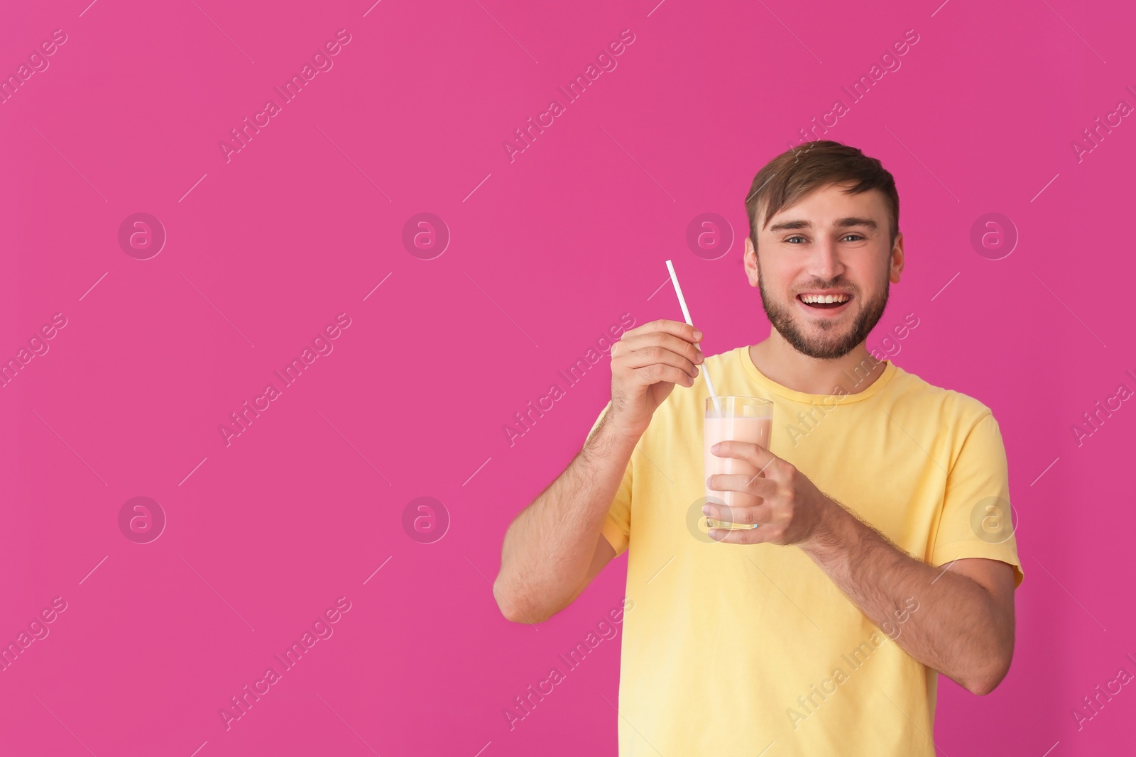 Photo of Young man with glass of delicious milk shake on color background