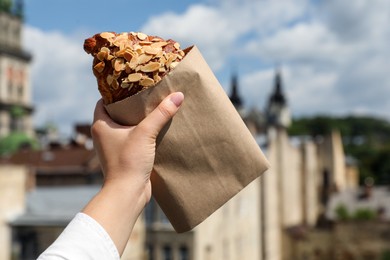 Photo of Woman with delicious croissant outdoors, closeup view