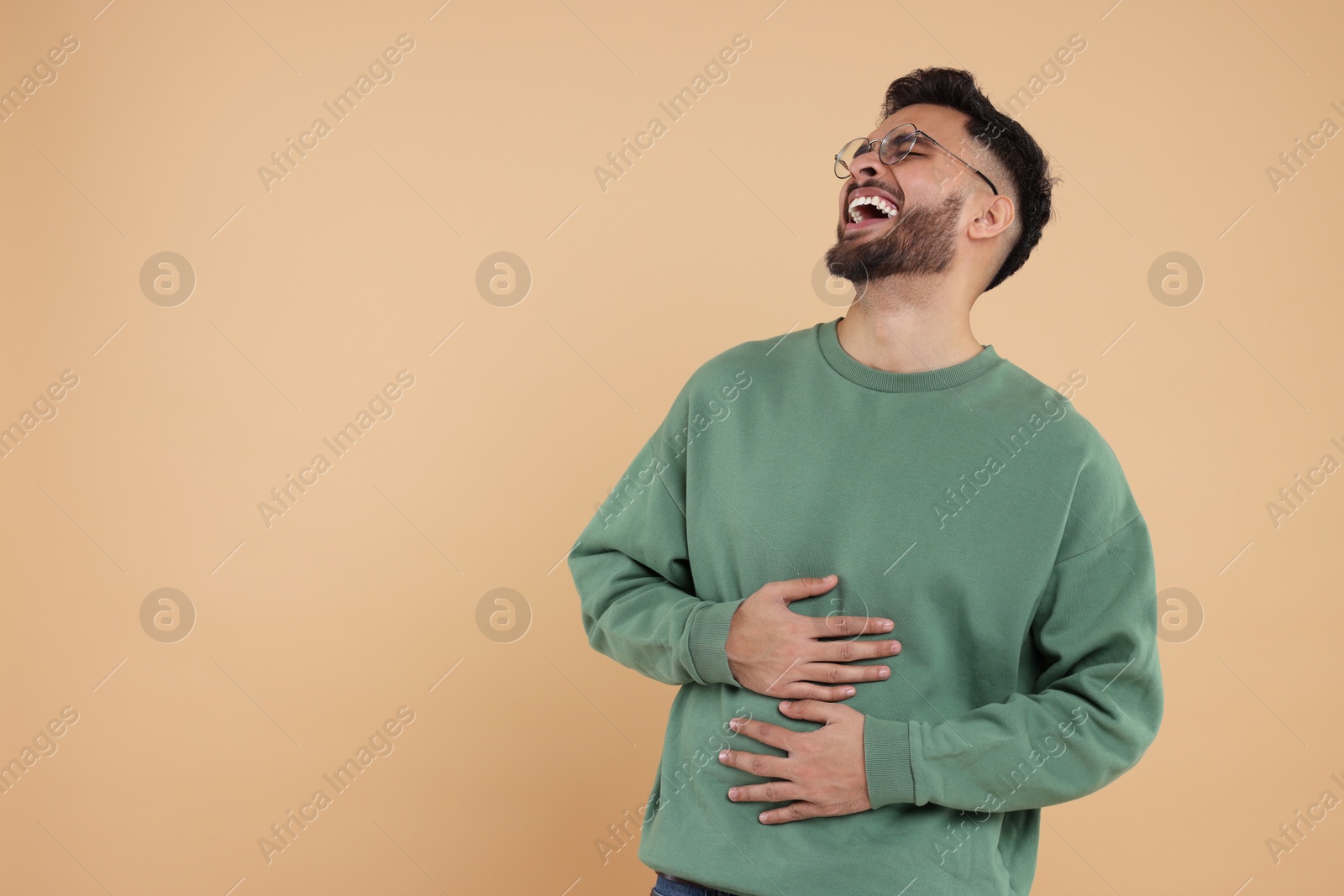 Photo of Handsome young man laughing on beige background, space for text