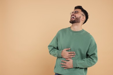 Handsome young man laughing on beige background, space for text