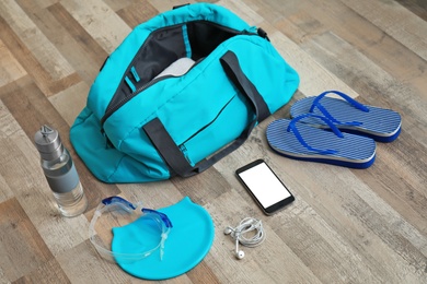 Photo of Sports bag and equipment for swimming pool on wooden floor