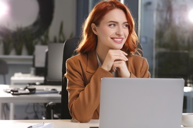 Happy woman working with laptop at white desk in office
