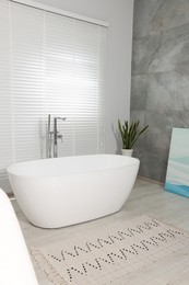 Photo of Stylish bathroom interior with ceramic tub and houseplant