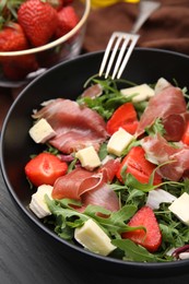 Photo of Tasty salad with brie cheese, prosciutto and strawberries on table, closeup