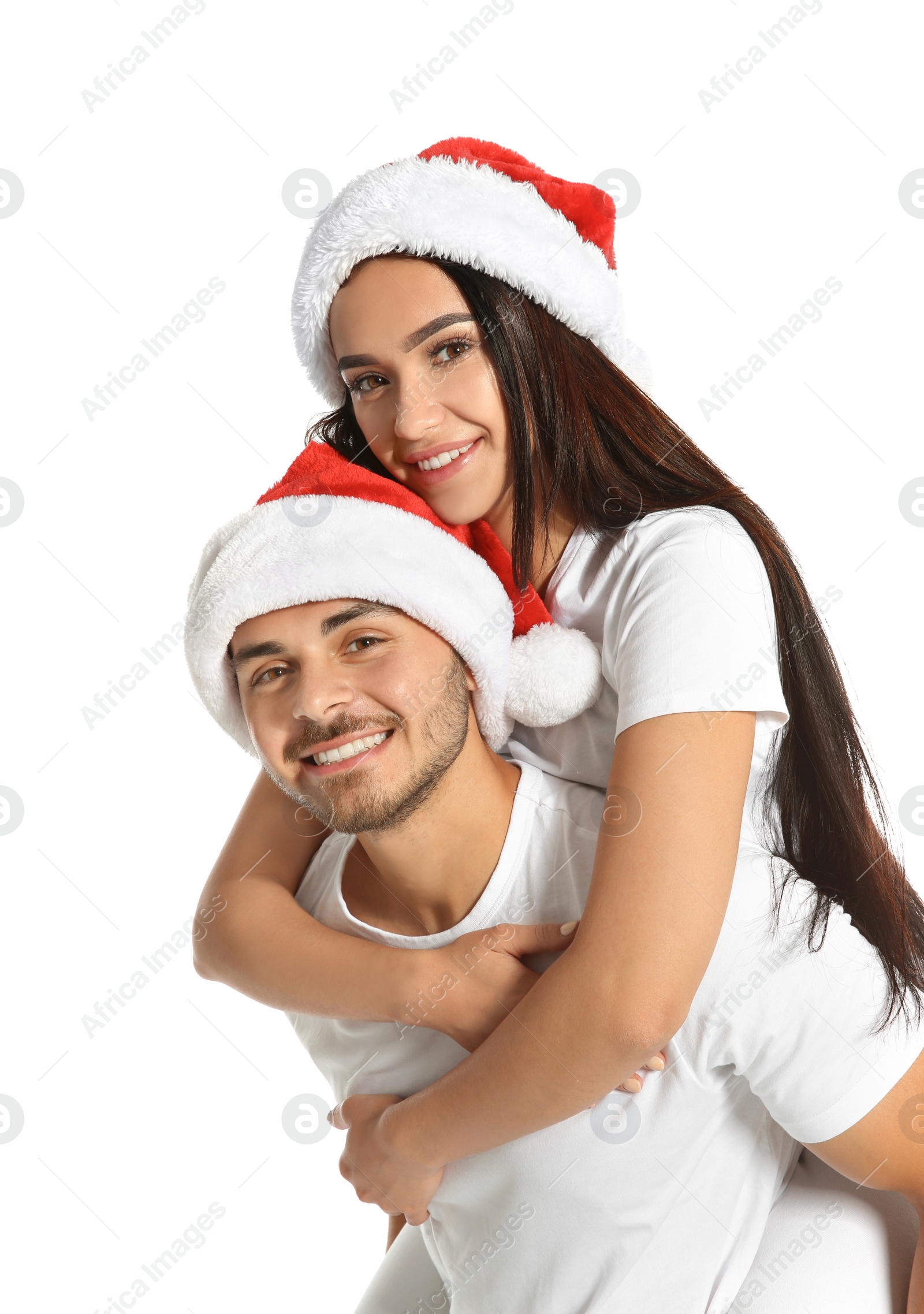 Photo of Young happy couple with Santa hats on white background. Christmas celebration