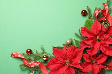 Photo of Flat lay composition with poinsettias (traditional Christmas flowers) and holiday decor on green background. Space for text
