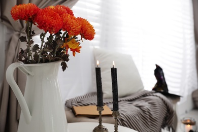 Black candles and flowers on table in room. Idea for festive interior