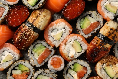 Different tasty sushi rolls as background, top view