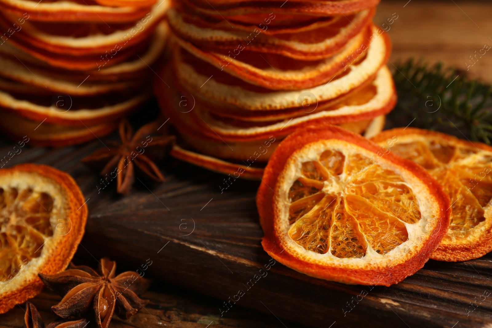 Photo of Dry orange slices and anise stars on wooden board, closeup