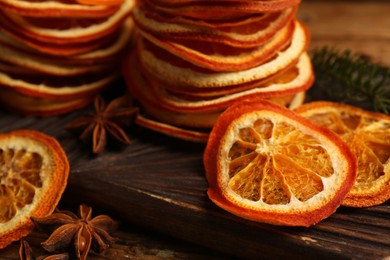 Photo of Dry orange slices and anise stars on wooden board, closeup