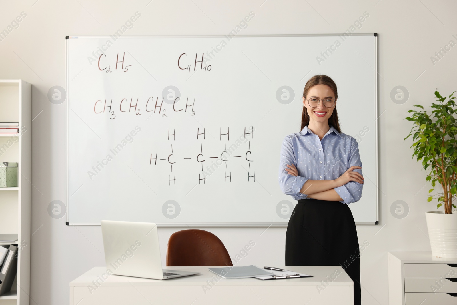 Photo of Portrait of young chemistry teacher near whiteboard in classroom. Space for text