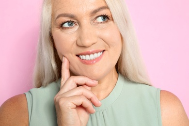 Photo of Portrait of mature woman with beautiful face on pink background