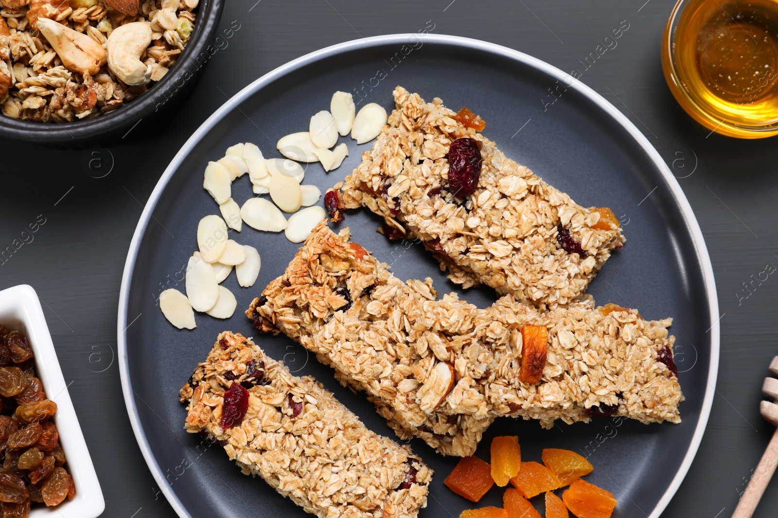 Photo of Tasty granola bars on grey wooden table, flat lay