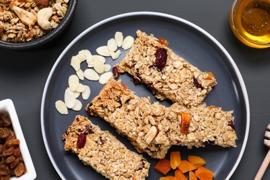 Photo of Tasty granola bars on grey wooden table, flat lay