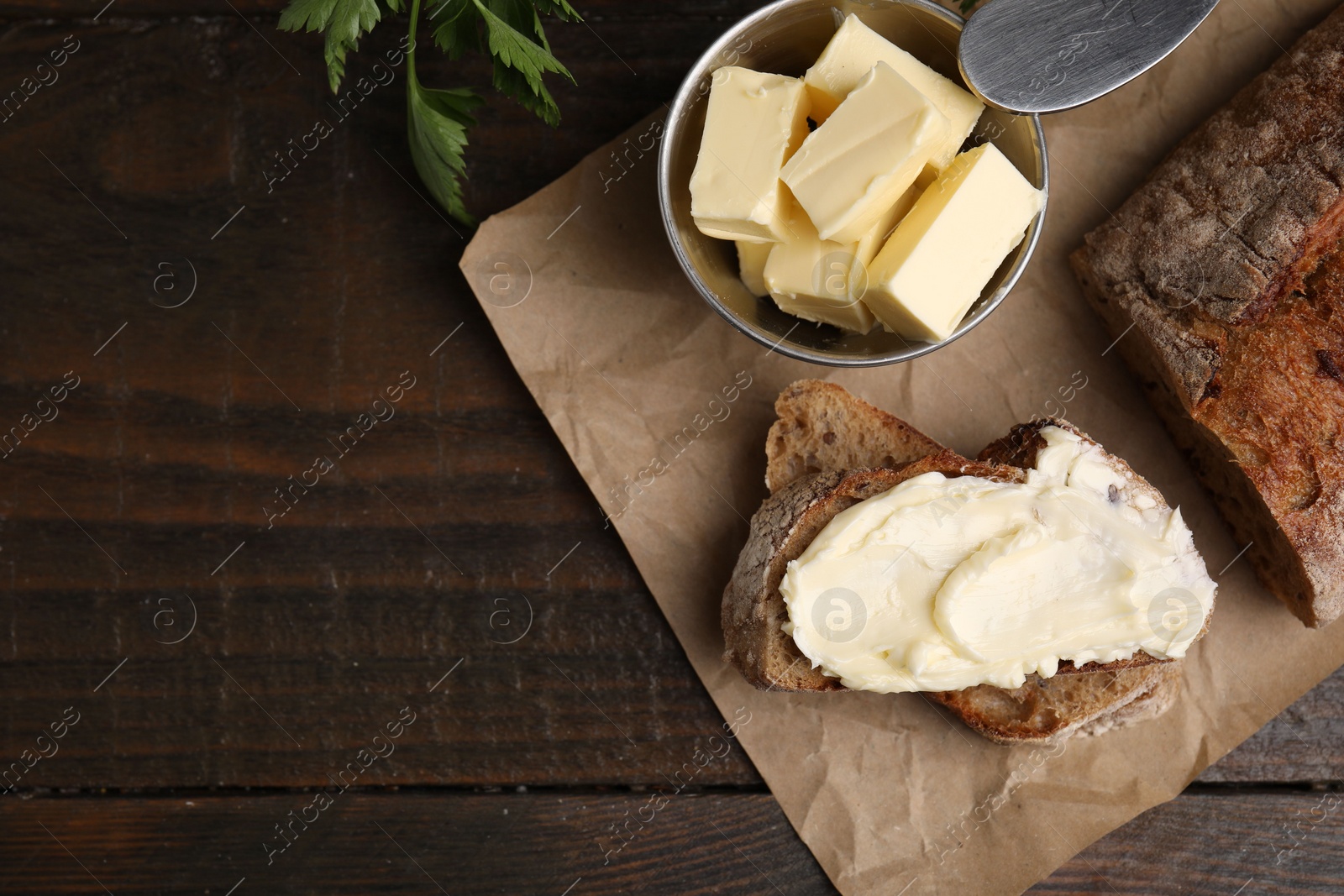 Photo of Tasty bread with butter on wooden table, flat lay. Space for text