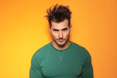 Young man with trendy hairstyle posing on color background