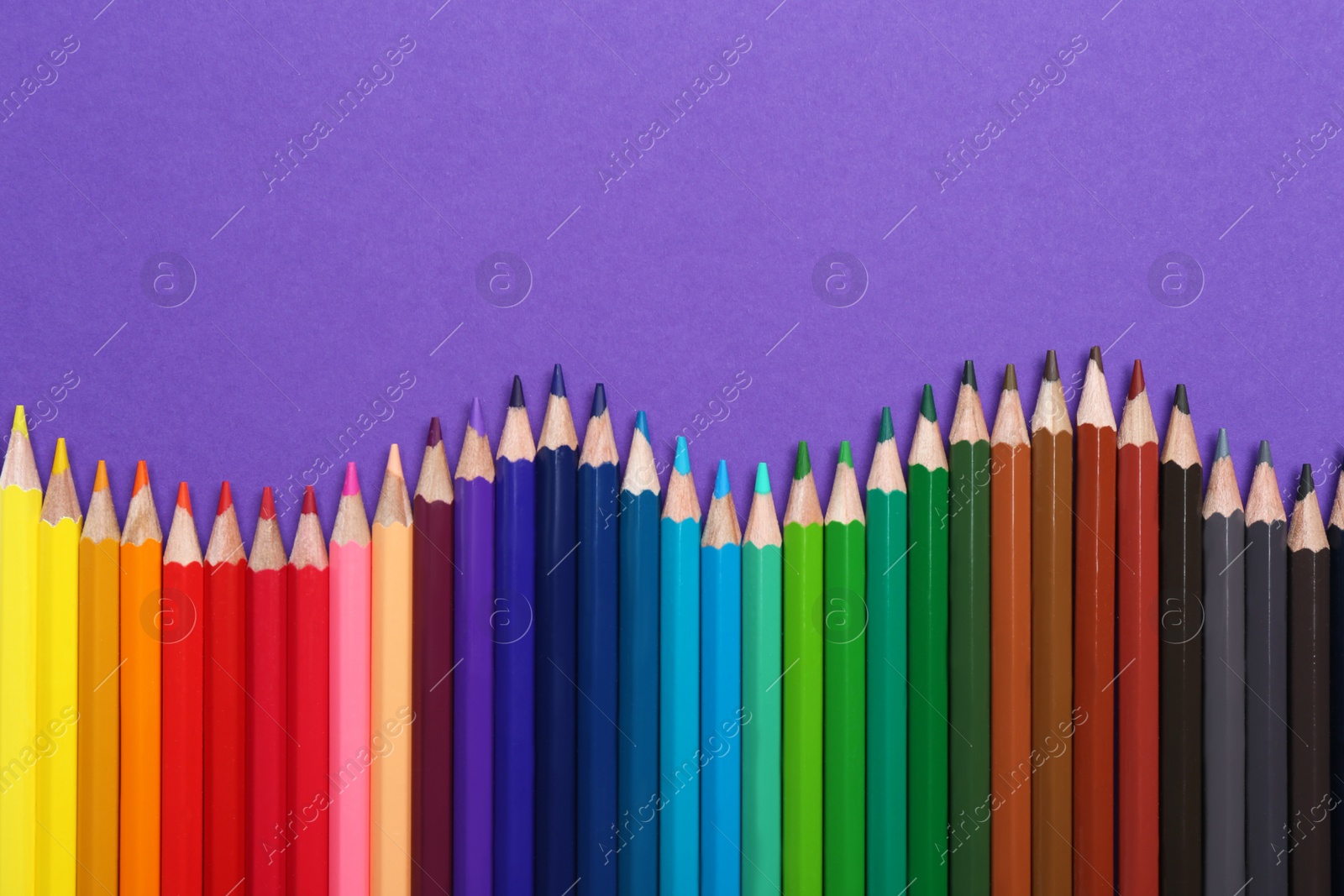 Photo of Colorful pencils on purple background, flat lay. Space for text