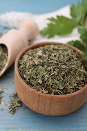 Photo of Dried parsley in bowl on light blue wooden table, closeup