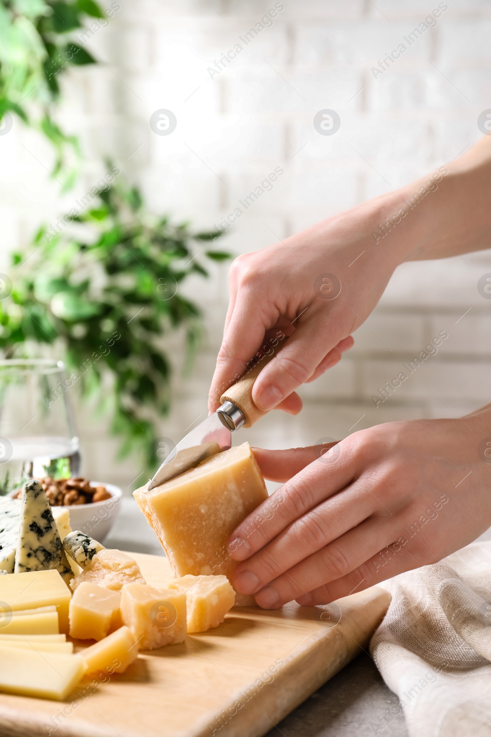 Photo of Woman cutting parmesan for cheese plate at table, closeup