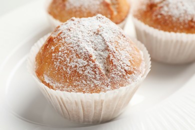 Photo of Tasty muffins powdered with sugar on plate, closeup