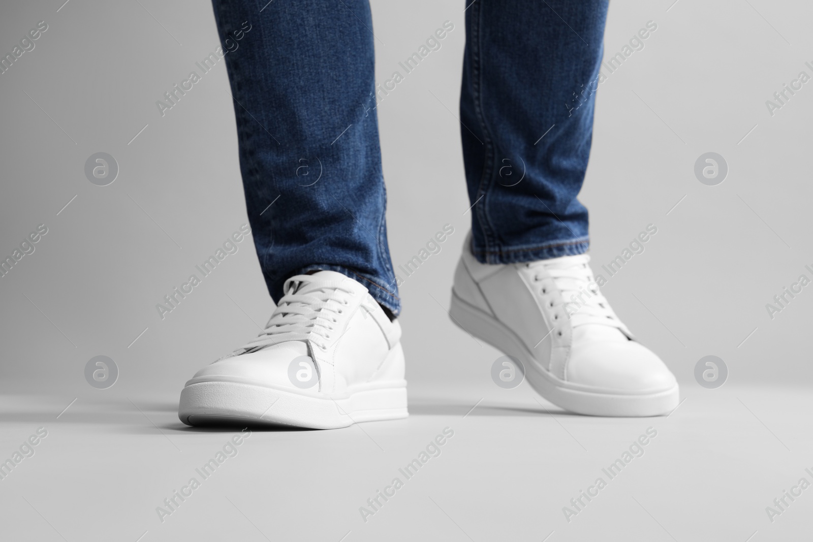 Photo of Man wearing stylish white sneakers on grey background, closeup