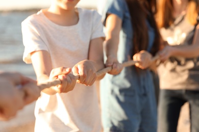 Photo of Children pulling rope during tug of war game outdoors, closeup. Summer camp