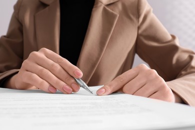 Photo of Woman signing document with pen, closeup view