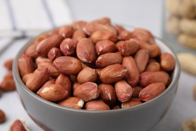 Fresh unpeeled peanuts in bowl on table, closeup