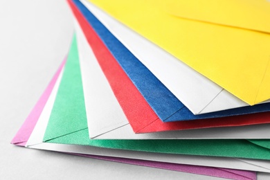 Photo of Stack of colorful paper envelopes on light background, closeup