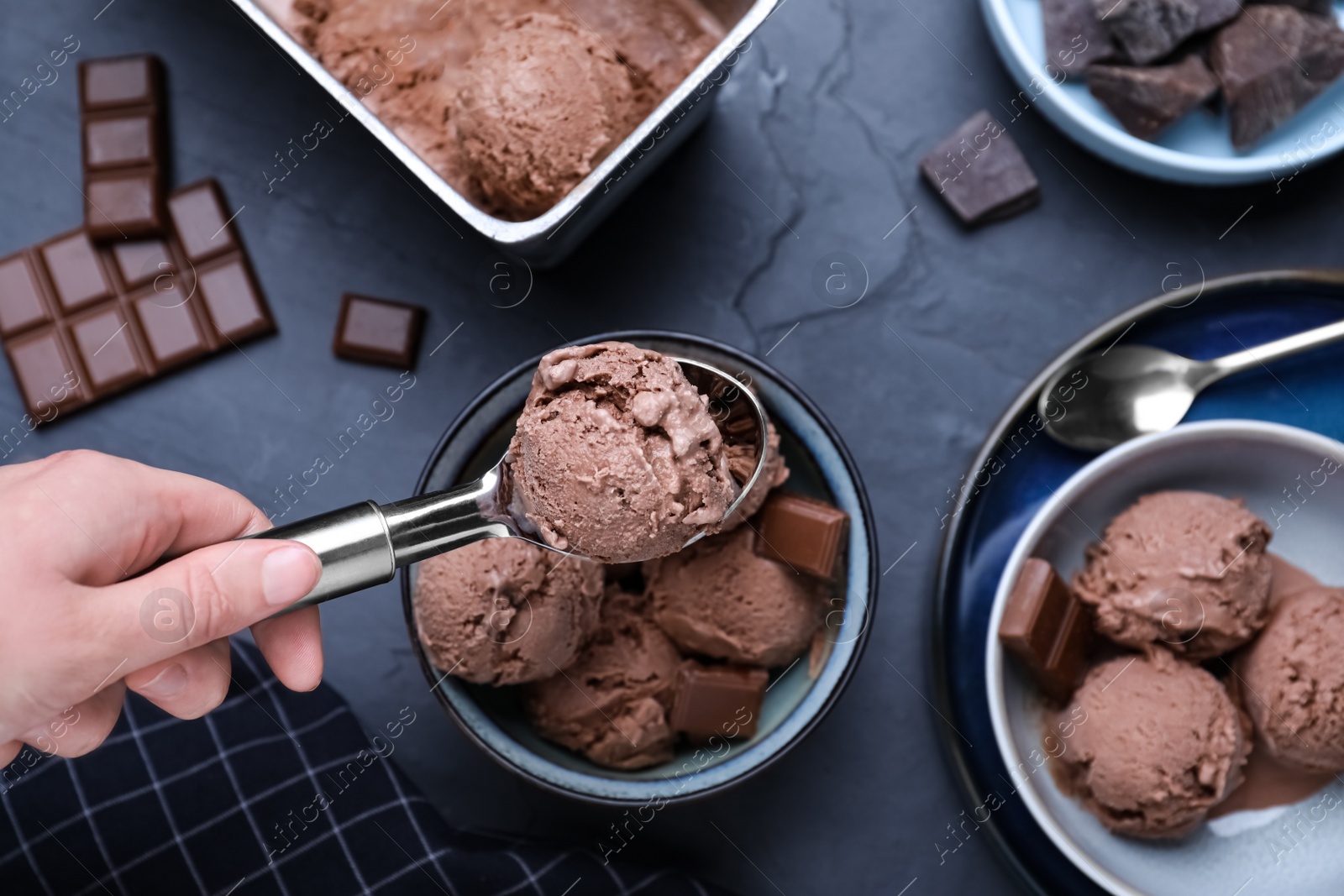 Photo of Woman putting chocolate ice cream into bowl at table with dessert, top view