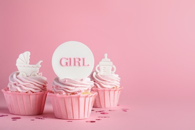Beautifully decorated baby shower cupcakes with cream and girl toppers on pink background. Space for text