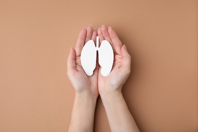 Quitting smoking concept. Woman holding paper lungs on beige background, top view