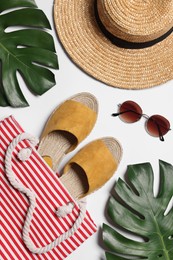 Flat lay composition with bag, green leaves and other beach accessories on white background
