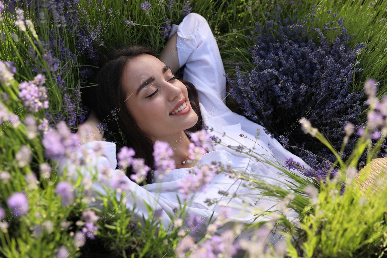 Photo of Young woman lying in lavender field on summer day