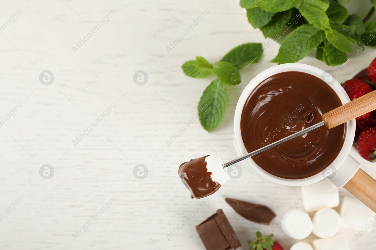 Photo of Flat lay composition with fondue pot and chocolate on white wooden table, space for text