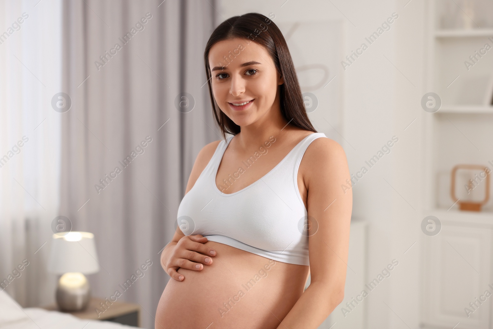 Photo of Beautiful pregnant woman wearing stylish comfortable underwear in bedroom