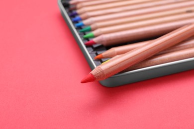 Box with many colorful pastel pencils on red background, closeup and space for text. Drawing supplies