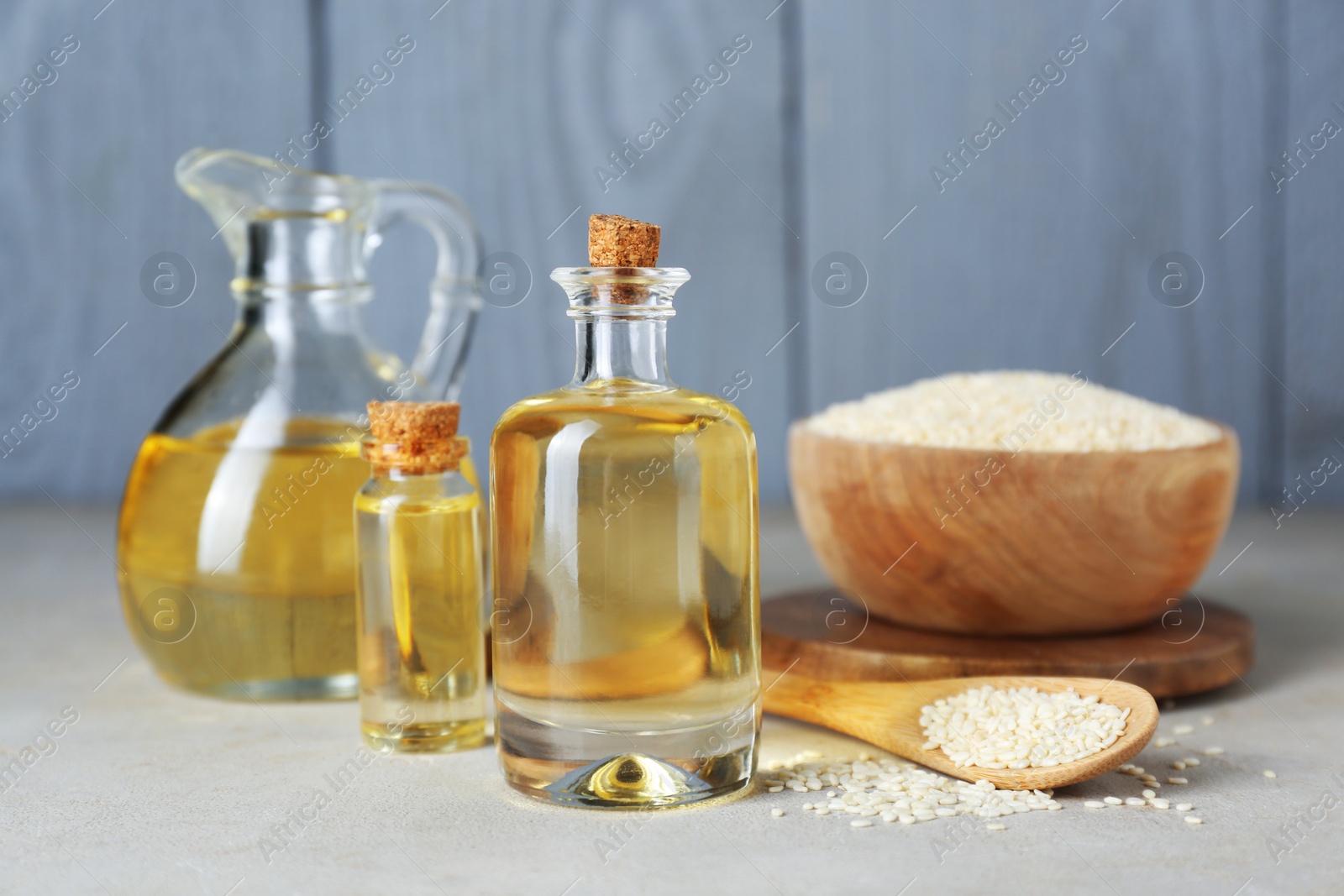 Photo of Sesame oil and seeds on light grey table