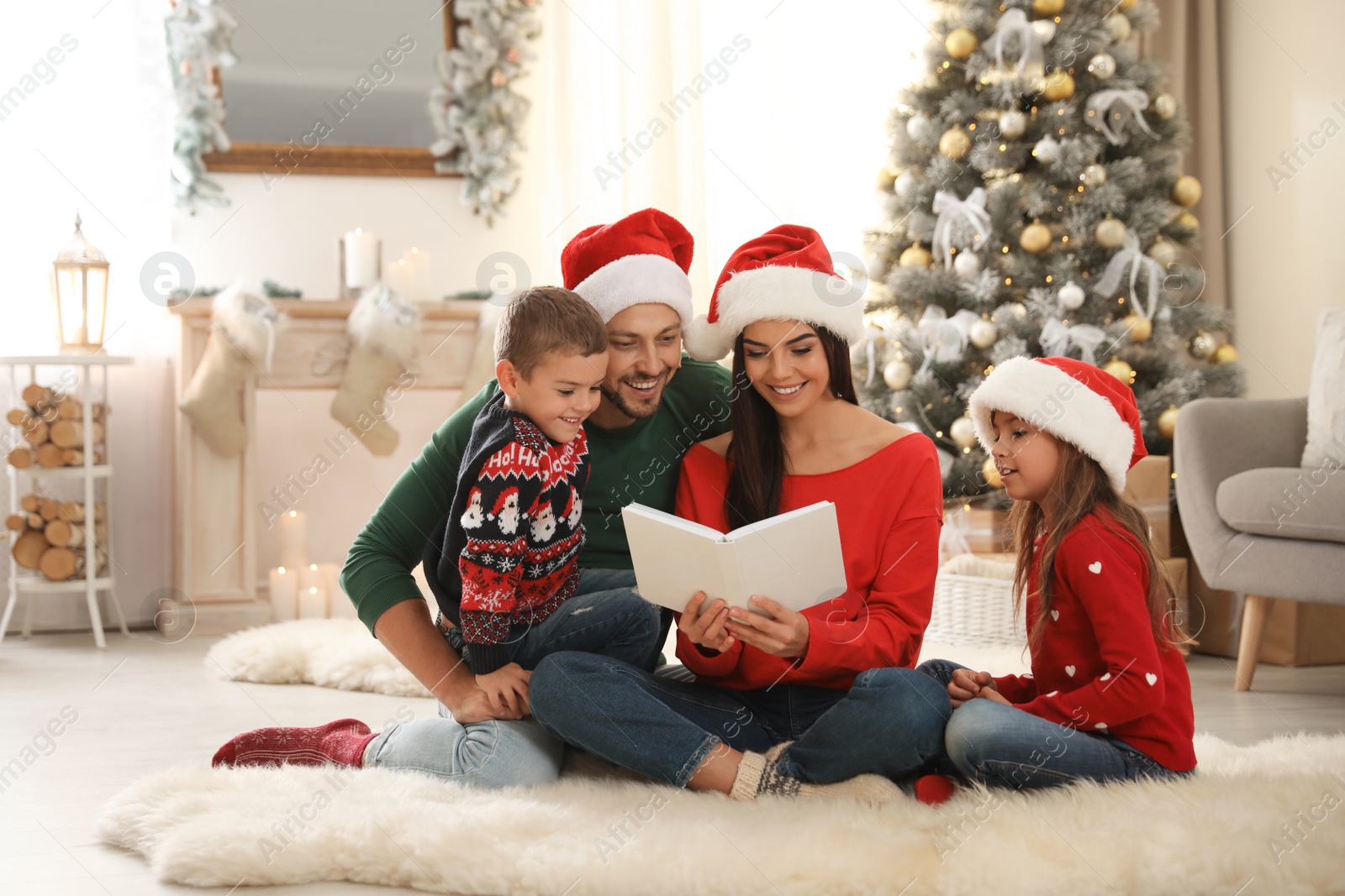 Photo of Happy family in Santa hats reading book on floor at home