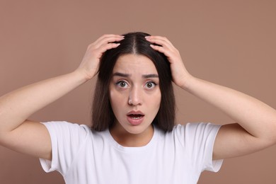 Emotional woman with healthy hair on beige background. Dandruff problem